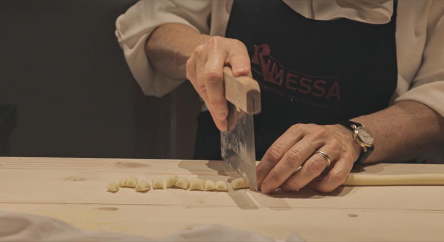 Chef in a Rimessa apron cutting fresh pasta by hand