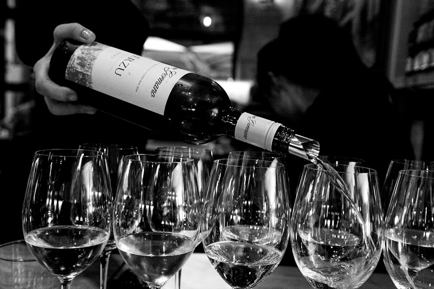 A sommelier pouring wine into a row of glasses at Rimessa Roscioli